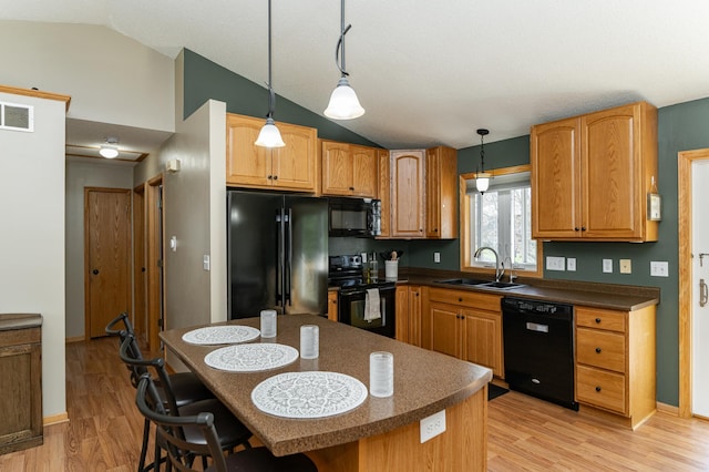 kitchen featuring black appliances, a sink, lofted ceiling, dark countertops, and light wood finished floors