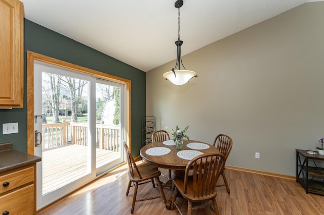 dining area featuring vaulted ceiling, light wood-type flooring, and baseboards