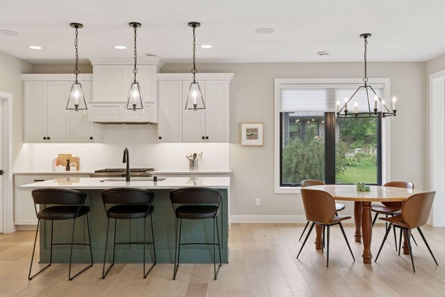 16798 Stirrup Ln, Eden Prairie, MN 55347 - kitchen with a sink, light wood-style floors, light countertops, an island with sink, and white cabinets