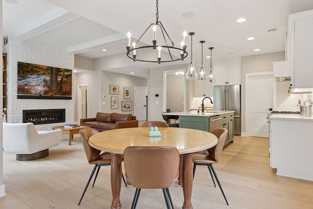 16798 Stirrup Ln, Eden Prairie, MN 55347 - dining area with light wood-style floors, a chandelier, beam ceiling, a brick fireplace, and recessed lighting