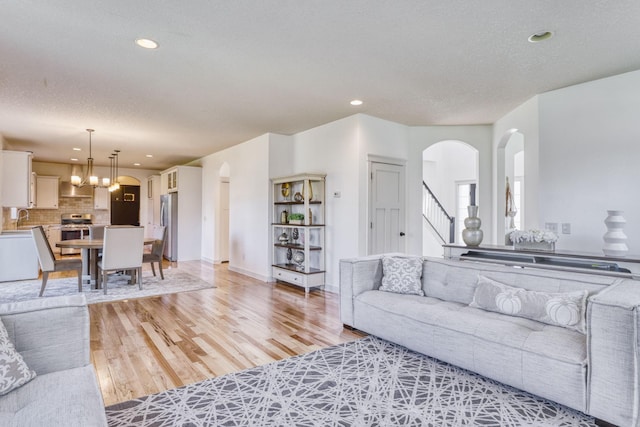 1730 Deephaven Dr, Woodbury, MN 55129 - living area with arched walkways, light wood finished floors, recessed lighting, stairs, and a textured ceiling