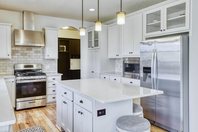 1730 Deephaven Dr, Woodbury, MN 55129 - kitchen with appliances with stainless steel finishes, wall chimney exhaust hood, white cabinets, tasteful backsplash, and a center island