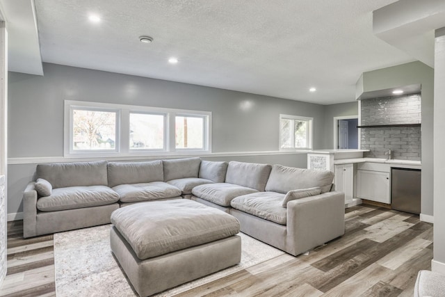1730 Deephaven Dr, Woodbury, MN 55129 - living room featuring a textured ceiling, recessed lighting, light wood-type flooring, bar area, and baseboards