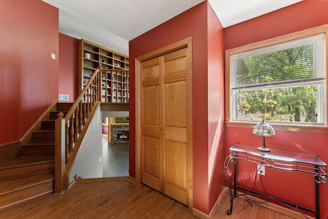 hallway with baseboards, wood finished floors, and stairway