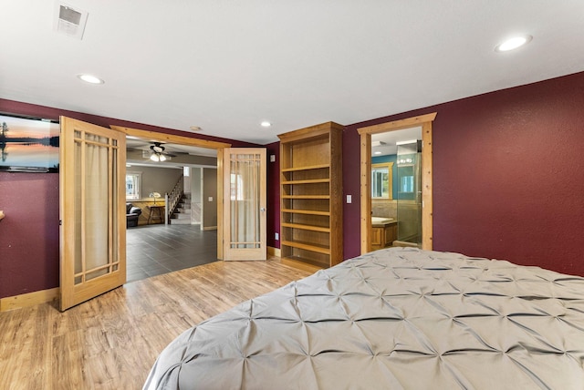 bedroom with wood finished floors, recessed lighting, baseboards, and ensuite bath