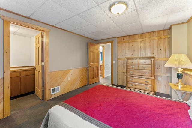 bedroom with wood walls, a wainscoted wall, carpet floors, and ornamental molding