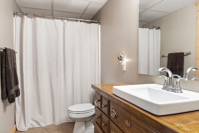 bathroom featuring a drop ceiling, toilet, vanity, and tile patterned floors