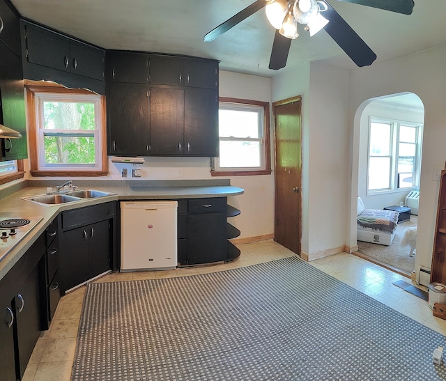 kitchen featuring dishwasher, a sink, a ceiling fan, arched walkways, and dark cabinets