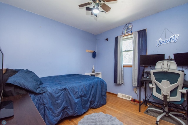 bedroom featuring a desk, wood finished floors, baseboards, and ceiling fan