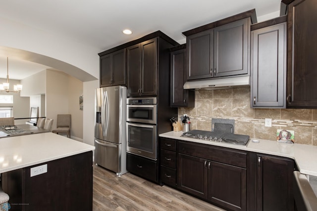 3313 5th Way E Unit B, West Fargo, ND 58078 - kitchen featuring stainless steel appliances, under cabinet range hood, arched walkways, light wood finished floors, and light countertops