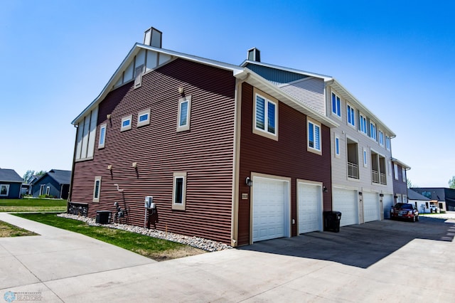 3313 5th Way E Unit B, West Fargo, ND 58078 - view of side of property with a chimney, an attached garage, driveway, and cooling unit