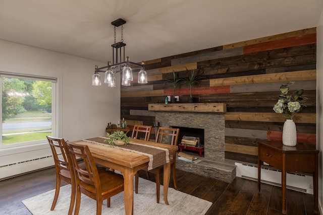 615 Vine St, Hudson, WI 54016 - dining room with a baseboard heating unit, wood-type flooring, a stone fireplace, wooden walls, and baseboard heating