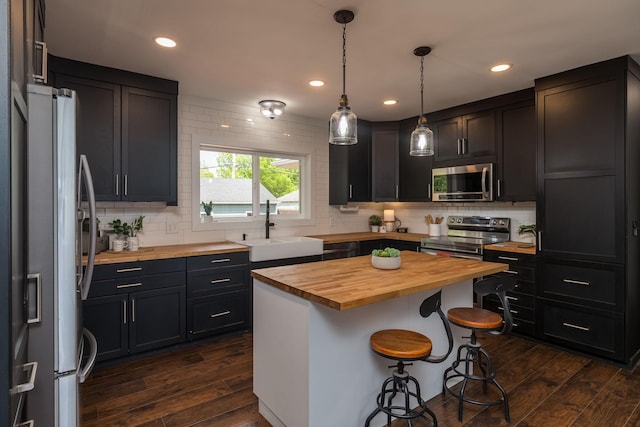615 Vine St, Hudson, WI 54016 - kitchen with wood counters, stainless steel appliances, a sink, a breakfast bar, and tasteful backsplash