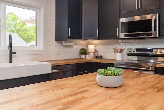 615 Vine St, Hudson, WI 54016 - kitchen with butcher block countertops, appliances with stainless steel finishes, decorative backsplash, and a sink