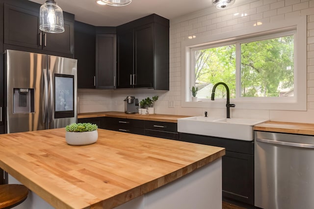 615 Vine St, Hudson, WI 54016 - kitchen with butcher block countertops, stainless steel appliances, a sink, decorative backsplash, and pendant lighting