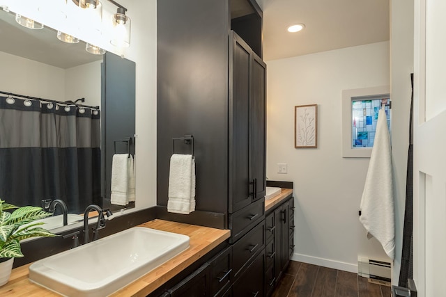 615 Vine St, Hudson, WI 54016 - full bath with baseboard heating, double vanity, wood finished floors, baseboards, and recessed lighting