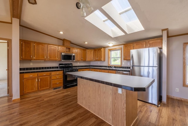 36308 Edgewood Rd, Harmony, MN 55939 - kitchen with appliances with stainless steel finishes, a skylight, vaulted ceiling, brown cabinets, and light wood-style floors