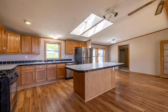 36308 Edgewood Rd, Harmony, MN 55939 - kitchen featuring stainless steel appliances, a skylight, wood finished floors, brown cabinets, and lofted ceiling