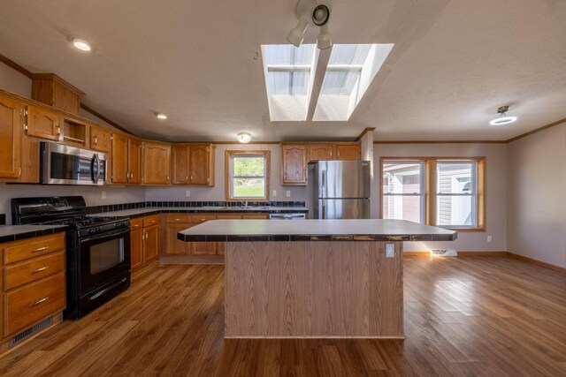 36308 Edgewood Rd, Harmony, MN 55939 - kitchen featuring appliances with stainless steel finishes, tile countertops, wood finished floors, a center island, and crown molding