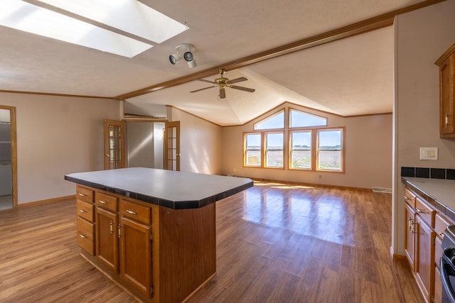 36308 Edgewood Rd, Harmony, MN 55939 - kitchen featuring a skylight, brown cabinets, a center island, wood finished floors, and crown molding