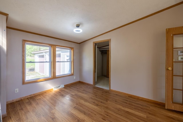 36308 Edgewood Rd, Harmony, MN 55939 - empty room featuring lofted ceiling, light wood-style floors, crown molding, baseboards, and a textured ceiling