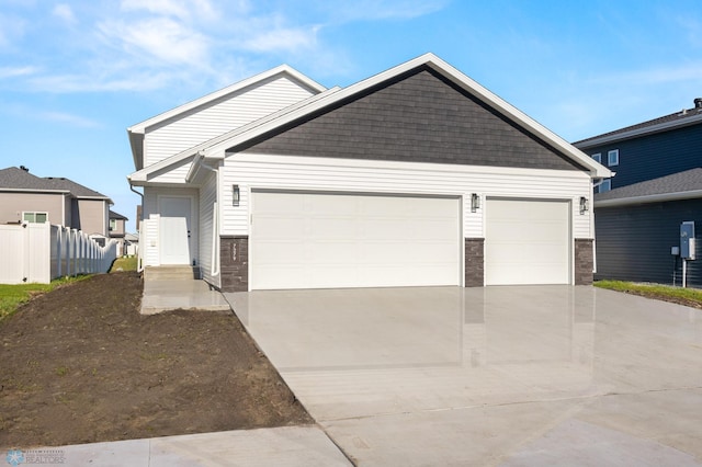 7279 26th St S, Fargo, ND 58104 - view of front of house featuring an attached garage, concrete driveway, fence, and stone siding