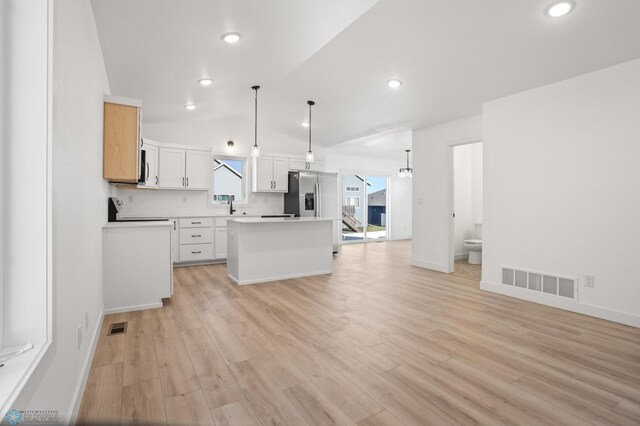 7279 26th St S, Fargo, ND 58104 - kitchen featuring stainless steel refrigerator with ice dispenser, a center island, light wood-type flooring, pendant lighting, and vaulted ceiling