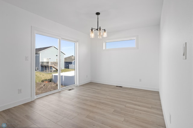 7279 26th St S, Fargo, ND 58104 - unfurnished room featuring a chandelier, light wood-style flooring, and baseboards