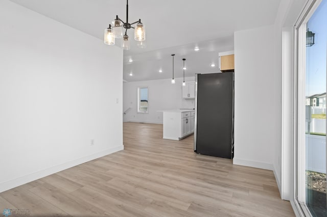 7279 26th St S, Fargo, ND 58104 - unfurnished living room with light wood-style flooring, a chandelier, and baseboards