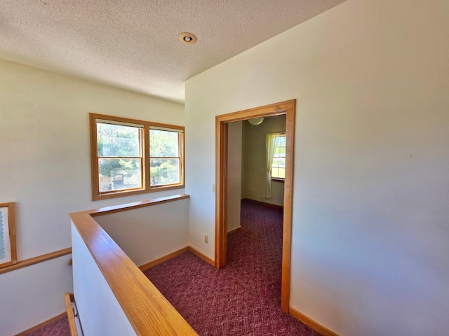 642 6th Ave, Calumet, MN 55716 - corridor featuring an upstairs landing, dark colored carpet, a textured ceiling, and baseboards