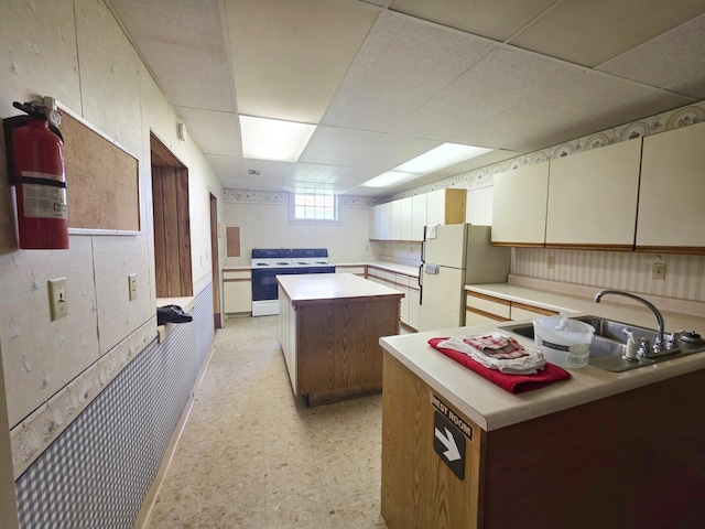 642 6th Ave, Calumet, MN 55716 - kitchen with white appliances, a kitchen island, a drop ceiling, a sink, and light countertops