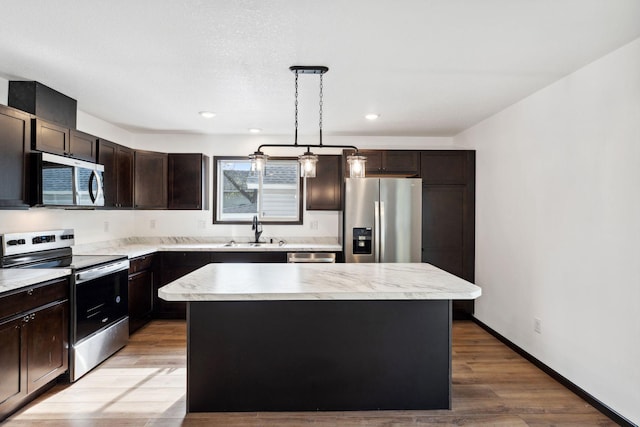 1094 7th St E, Saint Paul, MN 55106 - kitchen with appliances with stainless steel finishes, a sink, dark brown cabinets, a center island, and light countertops