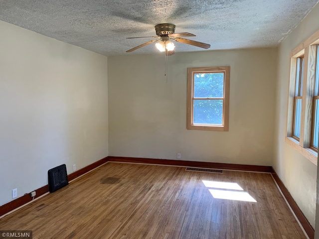 empty room with wood finished floors, baseboards, a textured ceiling, and ceiling fan