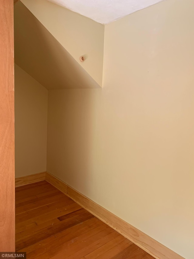additional living space with wood-type flooring and baseboards