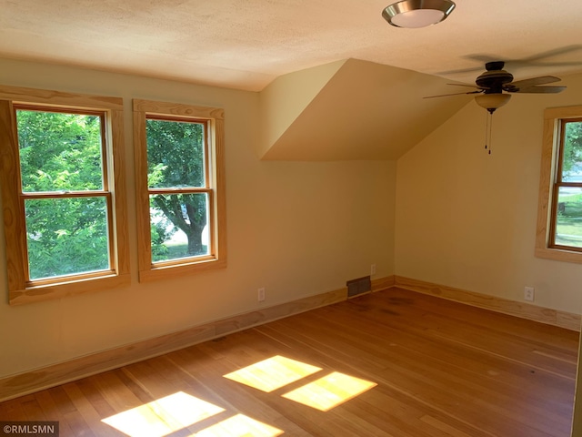 additional living space with hardwood / wood-style floors, a ceiling fan, and baseboards