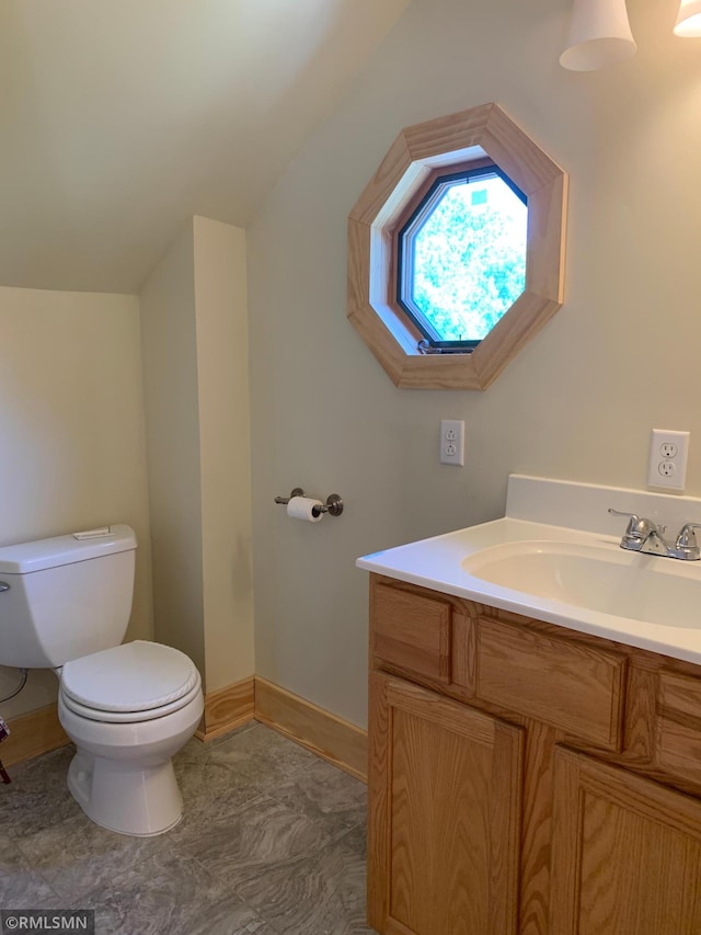 bathroom featuring toilet, vanity, and baseboards