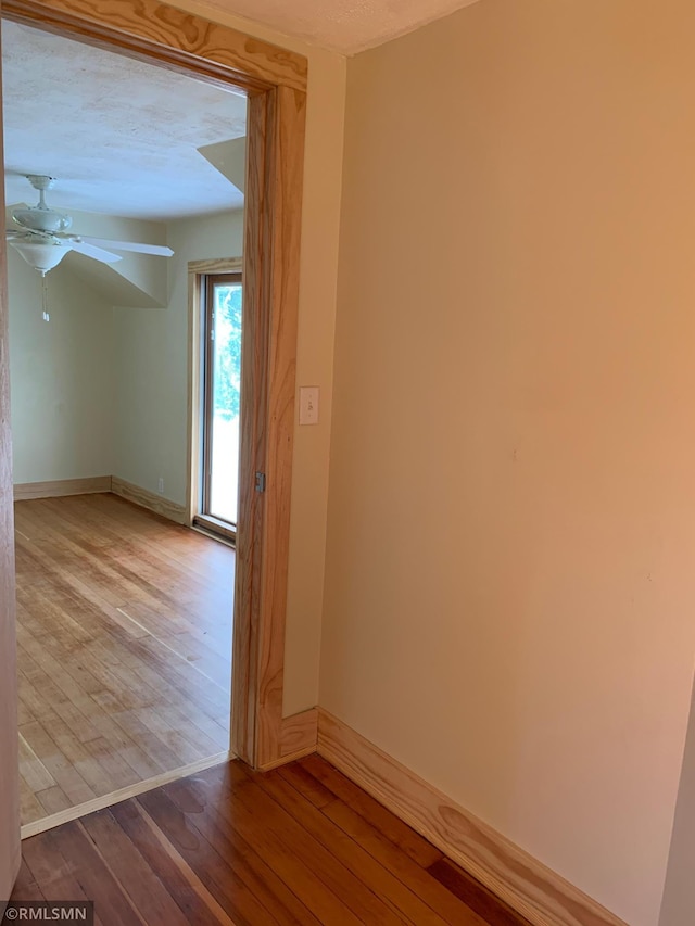empty room featuring wood-type flooring, baseboards, and a ceiling fan