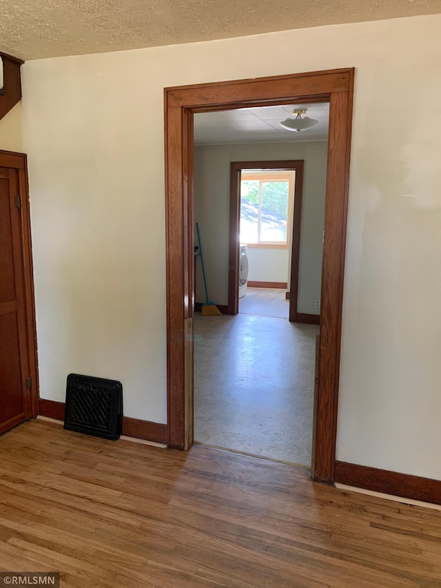 hall with baseboards, light wood finished floors, and washer / dryer