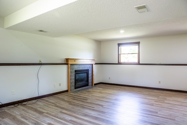 1377 Parkview Dr, New Richmond, WI 54017 - unfurnished living room with wood finished floors, a tile fireplace, a textured ceiling, and baseboards
