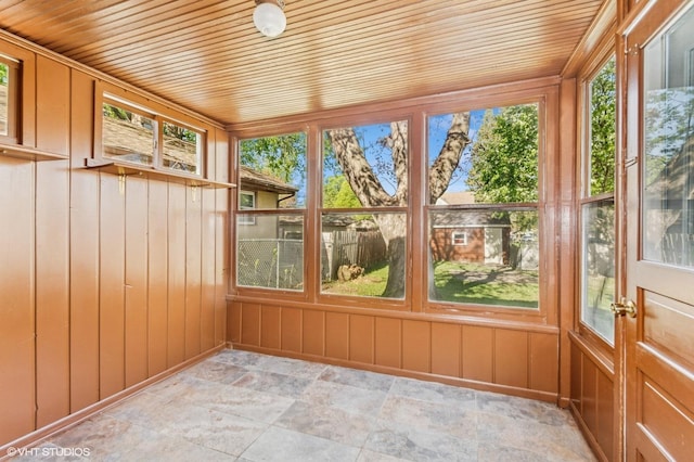 unfurnished sunroom with stone finish flooring, wood ceiling, and wood walls
