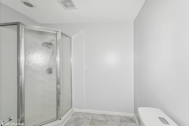 full bath with a shower stall, a textured ceiling, toilet, and baseboards