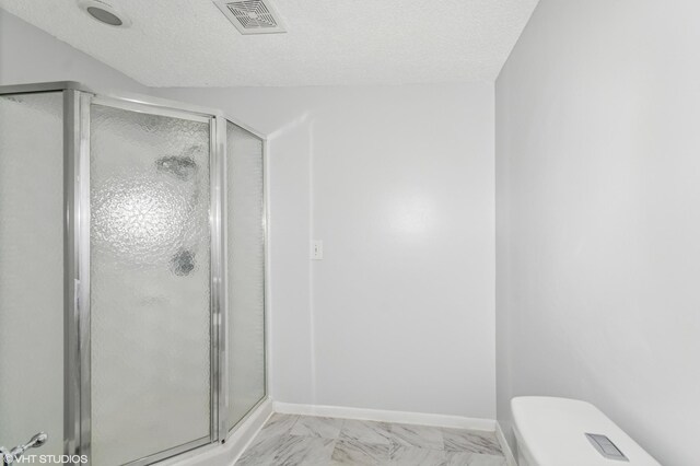 full bath with a shower stall, a textured ceiling, toilet, and baseboards