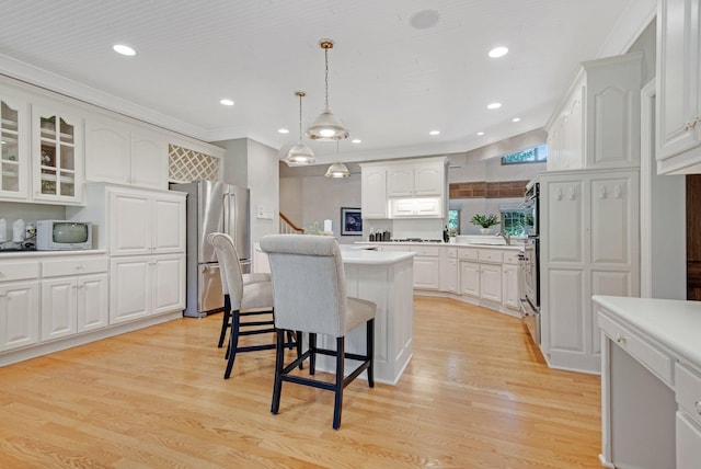 2 Pleasant Lake Rd, North Oaks, MN 55127 - kitchen featuring freestanding refrigerator, a kitchen island, a breakfast bar area, white cabinetry, and light countertops