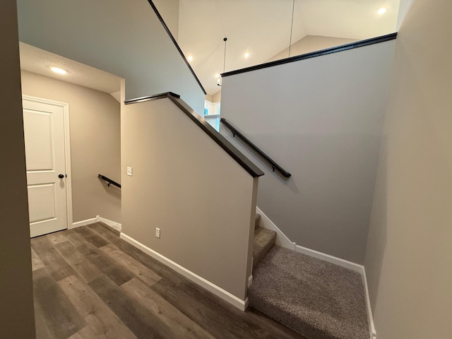 stairway with baseboards, recessed lighting, wood finished floors, and lofted ceiling