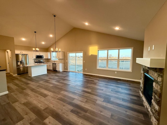 unfurnished living room featuring a chandelier, high vaulted ceiling, a fireplace, baseboards, and dark wood-type flooring