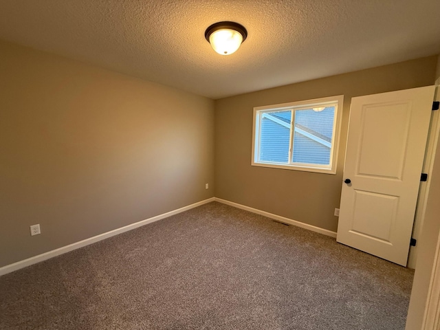 carpeted empty room with a textured ceiling and baseboards