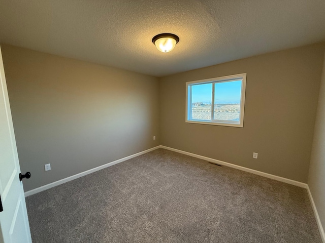 unfurnished room featuring dark colored carpet, a textured ceiling, and baseboards