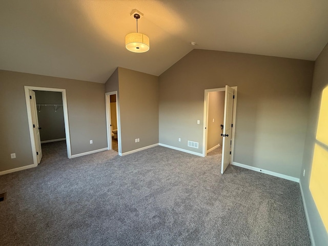 unfurnished bedroom featuring vaulted ceiling, a spacious closet, carpet floors, baseboards, and a closet