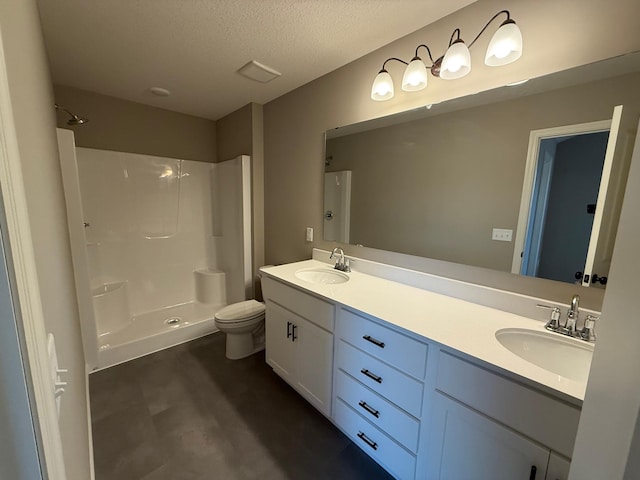 bathroom with a shower, toilet, double vanity, and a textured ceiling