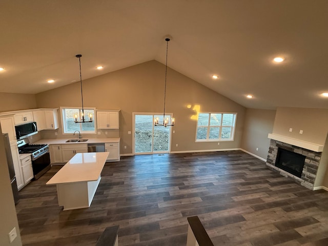kitchen with a chandelier, appliances with stainless steel finishes, open floor plan, high vaulted ceiling, and a sink
